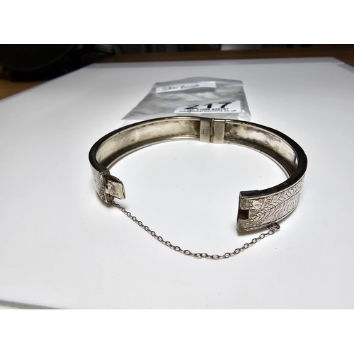 217 - A sterling silver hinged bangle with an engraved fern leaf sign, in clean condition, appears unmarke... 