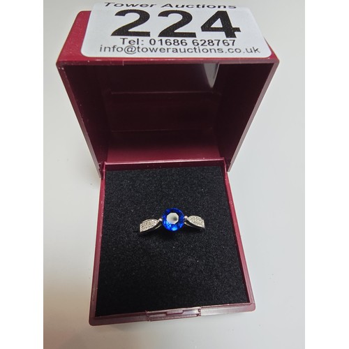 224 - A pretty 925 silver dress ring inset with a blue CZ crystal stone with smaller clear CZ stones to th... 