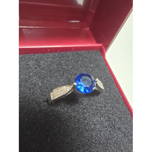 224 - A pretty 925 silver dress ring inset with a blue CZ crystal stone with smaller clear CZ stones to th... 