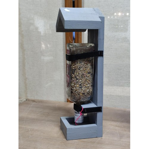 488 - 2x hand made bird feeders, each with a bottle filled with sead, self filling tray, height of 39cm