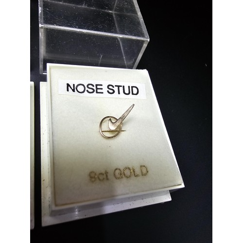 321 - 2x cased as new 9ct gold nose studs 1 with a Nike tick design the other with a clear crystal design.