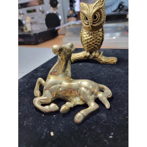 338 - A brass owl a brass horse at walk a brass horse lying down a brass dog a candle holder and a small c... 