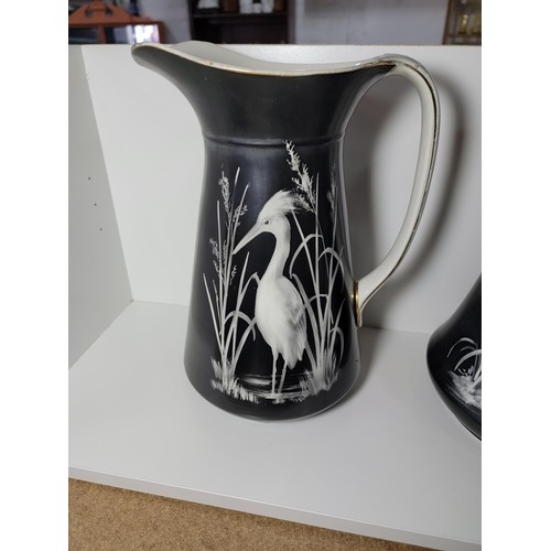 153 - Pair of large Lawleys black and white egret decorated jugs, both jugs have gilding to the handles, o... 