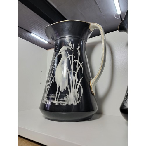 153 - Pair of large Lawleys black and white egret decorated jugs, both jugs have gilding to the handles, o... 