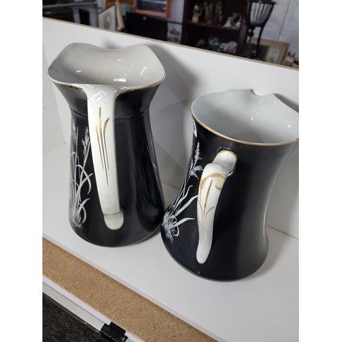 153 - Pair of large Lawleys black and white egret decorated jugs, both jugs have gilding to the handles, o... 