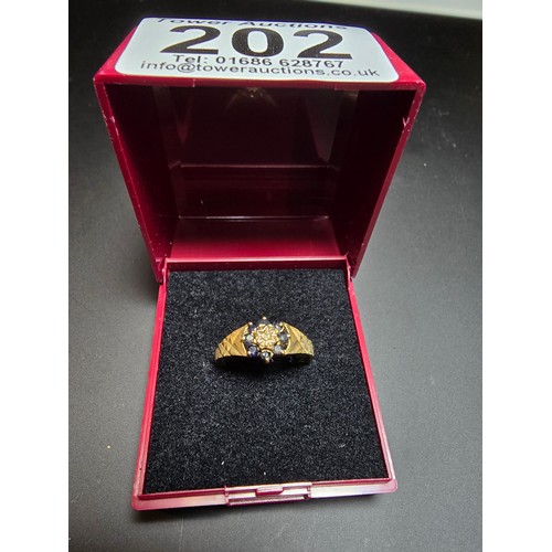 202 - A gold plate on solid 925 silver hallmarked ring inset with 8 sapphire stones and a diamond to the c... 