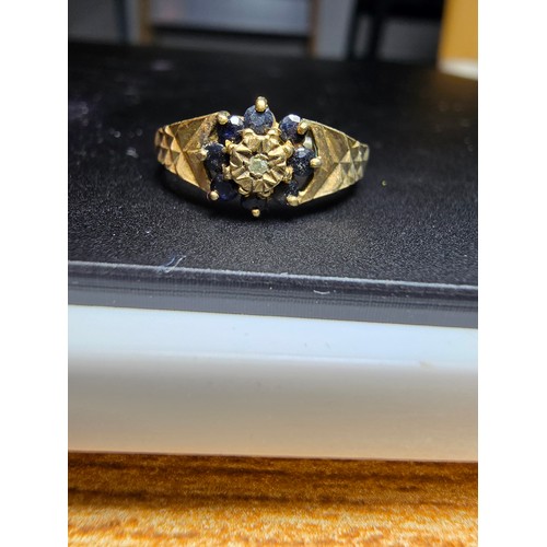 202 - A gold plate on solid 925 silver hallmarked ring inset with 8 sapphire stones and a diamond to the c... 