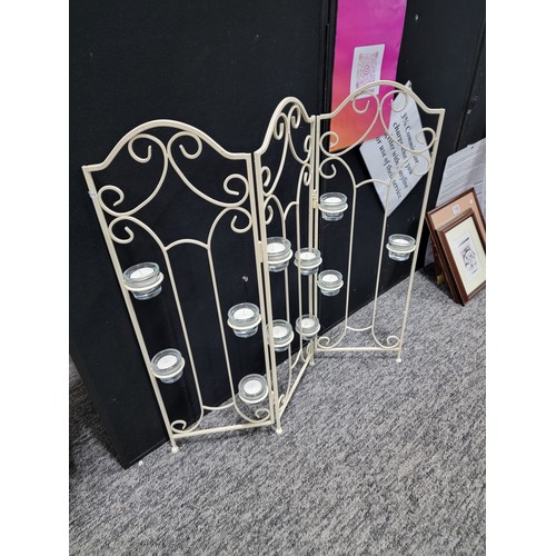 92 - A wrought iron tri-fold candle firescreen with 11x glass tea light holders, height 73cm length 65cm