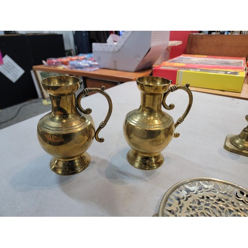 105 - A large brass jam pan containing a a quantity of brass items including 4 pair of candlesticks, 2 tal... 