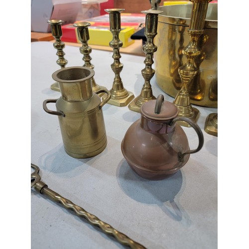 105 - A large brass jam pan containing a a quantity of brass items including 4 pair of candlesticks, 2 tal... 