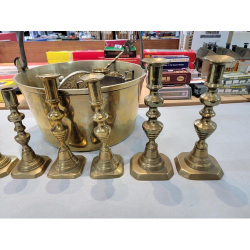 105 - A large brass jam pan containing a a quantity of brass items including 4 pair of candlesticks, 2 tal... 