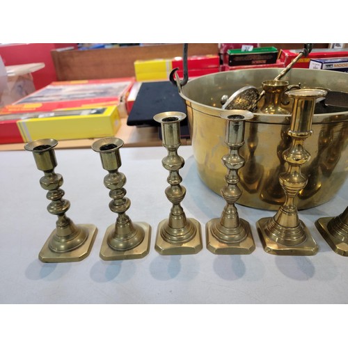 105 - A large brass jam pan containing a a quantity of brass items including 4 pair of candlesticks, 2 tal... 