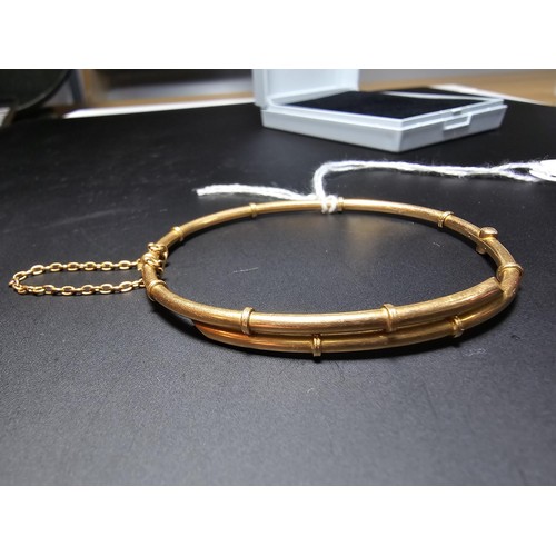 256 - 14ct Yellow Gold hinged Bangle in the form of bamboo complete with safety chain. Weight of 5.92 gram... 