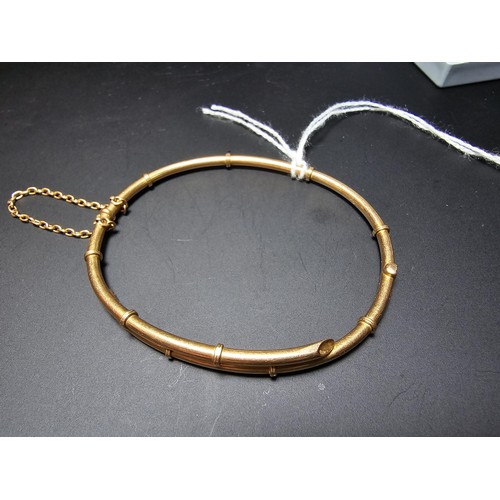 256 - 14ct Yellow Gold hinged Bangle in the form of bamboo complete with safety chain. Weight of 5.92 gram... 