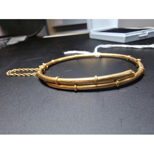 256 - 14ct Yellow Gold hinged Bangle in the form of bamboo complete with safety chain. Weight of 5.92 gram... 