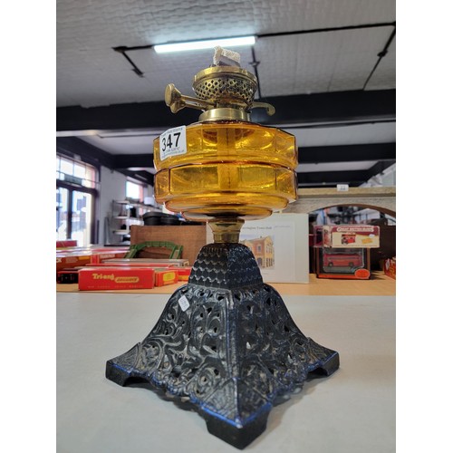 347 - A good quality oil lamp with an ornate blue cast iron base and an amber glass reservoir, with 2 unus... 