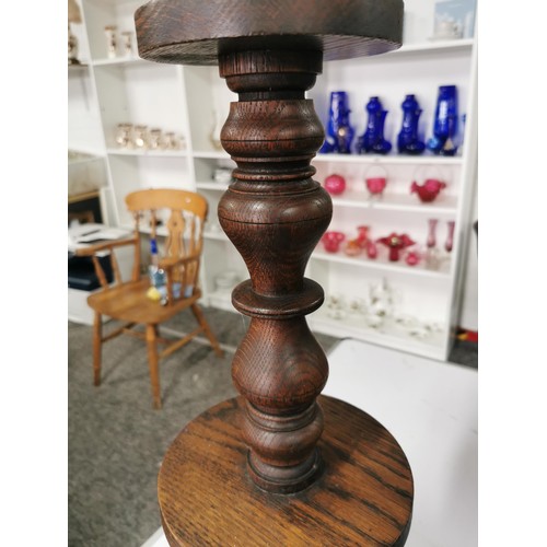 560 - Solid oak turned pillar candle stick with brass candle tray to top standing 60cm high