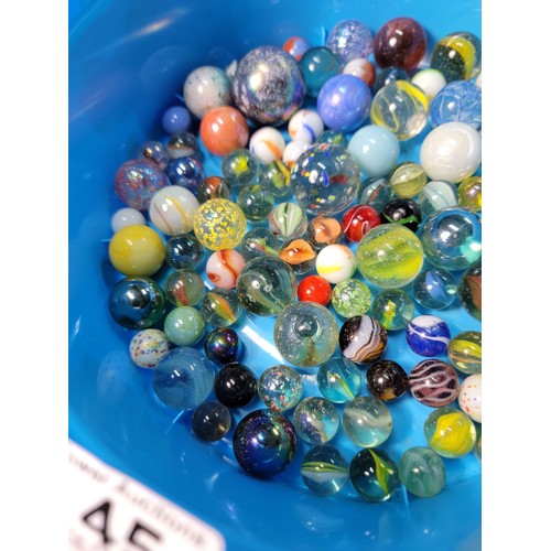 45 - A Cadbury Roses tub containing a quantity of various sized marbles inc large iridescent marbles, sol... 