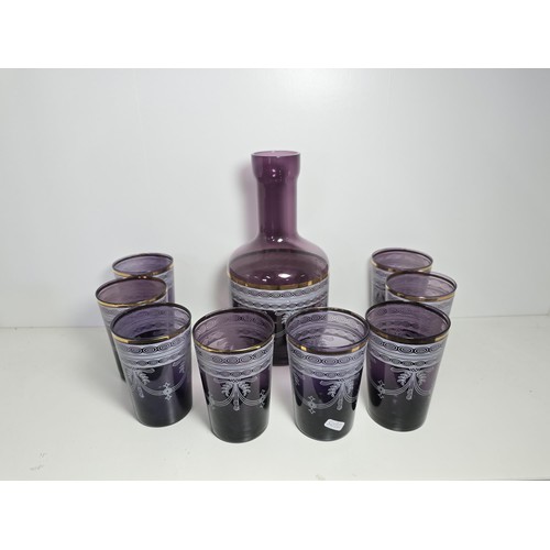 106 - A pretty amethyst glass drinking set to include an amethyst glass carafe along with a set of 9 match... 