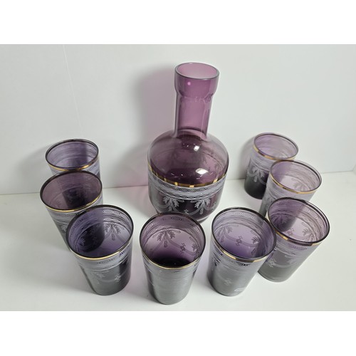 106 - A pretty amethyst glass drinking set to include an amethyst glass carafe along with a set of 9 match... 