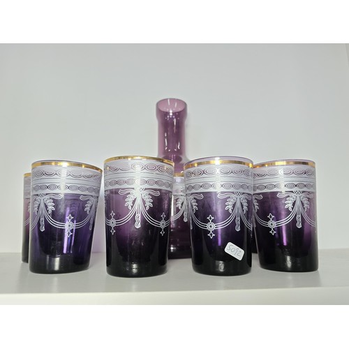 106 - A pretty amethyst glass drinking set to include an amethyst glass carafe along with a set of 9 match... 