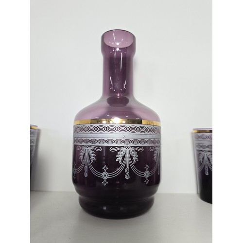 106 - A pretty amethyst glass drinking set to include an amethyst glass carafe along with a set of 9 match... 