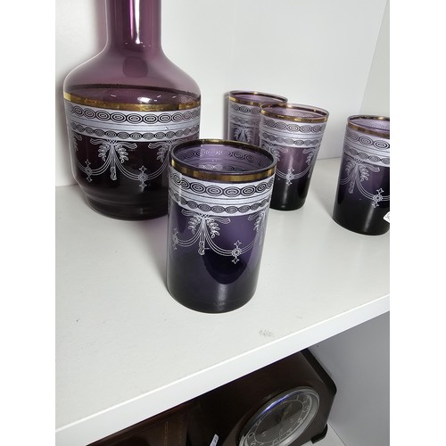 106 - A pretty amethyst glass drinking set to include an amethyst glass carafe along with a set of 9 match... 