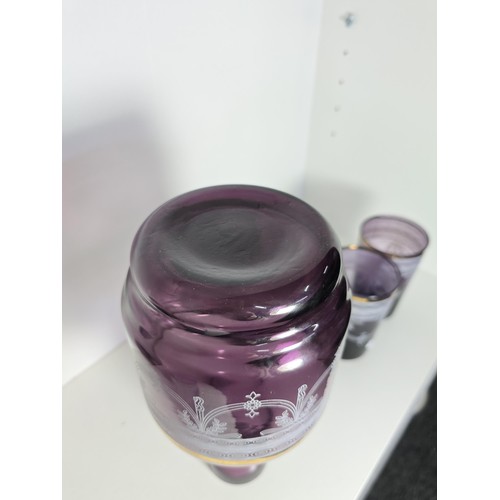 106 - A pretty amethyst glass drinking set to include an amethyst glass carafe along with a set of 9 match... 