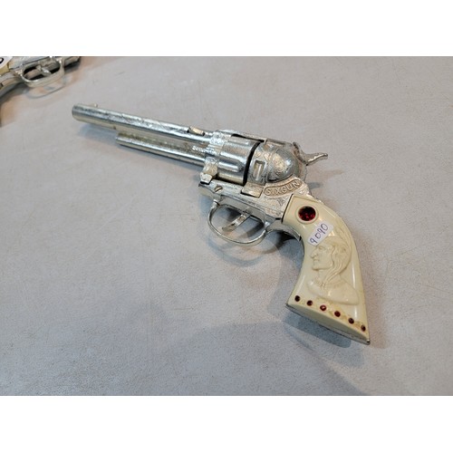 219 - Pair of vintage mid century BCM Sixgun cap gun, with red jewelled plastic handle depicting a native ... 