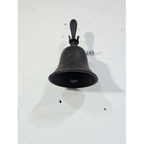 245 - An antique cast iron hand bell with a cast iron handle and a cast iron wall bracket marked Captain. ... 