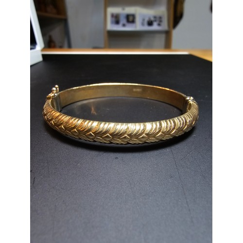 337 - A good quality hallmarked 9ct yellow gold bangle with an ornate design, opens on a spring hinge with... 