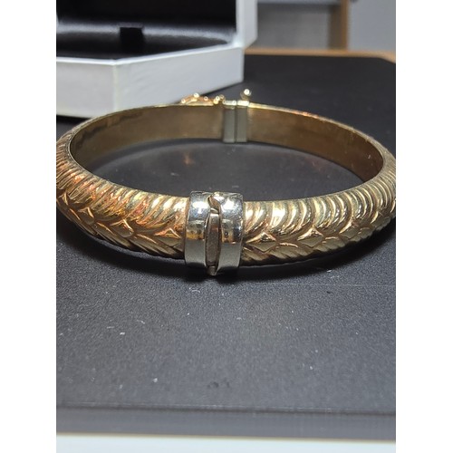 337 - A good quality hallmarked 9ct yellow gold bangle with an ornate design, opens on a spring hinge with... 