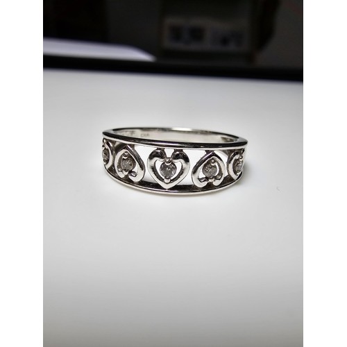 351 - A hallmarked 9ct white gold ring inset with 5 diamonds in heart shaped mounts, in excellent clean co... 