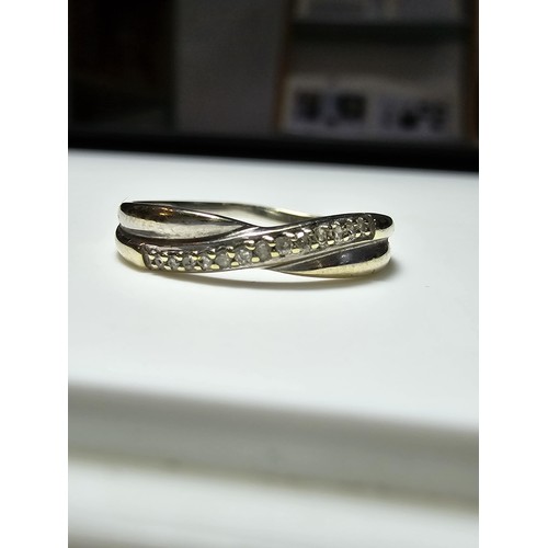 353 - A 9ct white gold crossover style ring inset with a band of diamonds, in excellent clean condition an... 