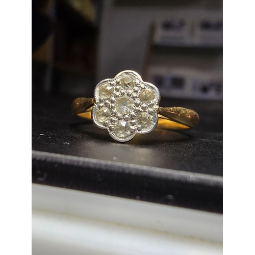 354 - A pretty 18ct yellow gold ring with a flower design inset with 7 white topaz gemstones and marked 18... 