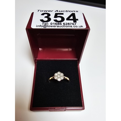 354 - A pretty 18ct yellow gold ring with a flower design inset with 7 white topaz gemstones and marked 18... 