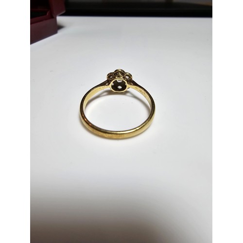 354 - A pretty 18ct yellow gold ring with a flower design inset with 7 white topaz gemstones and marked 18... 