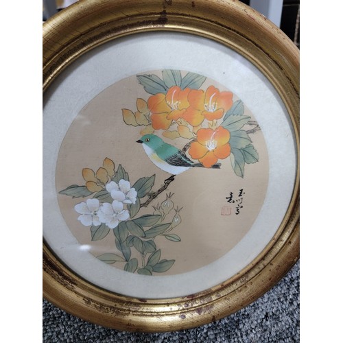 406 - 2x circular framed and glazed silk oriental pictures of birds both are signed along with a large gil... 