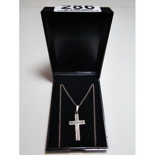 286 - An ornate 925 silver cross pendant with an engraved design set on a long 22