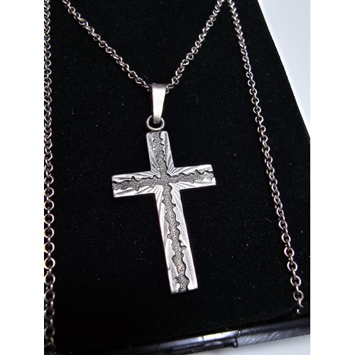 286 - An ornate 925 silver cross pendant with an engraved design set on a long 22