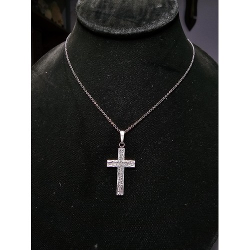 286 - An ornate 925 silver cross pendant with an engraved design set on a long 22