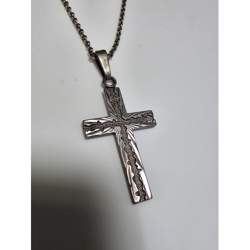 286 - An ornate 925 silver cross pendant with an engraved design set on a long 22