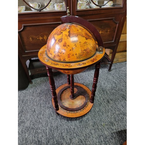 425 - Modern reproduction drinks globe standing on three castors, with a terrestrial globe scene to the to... 