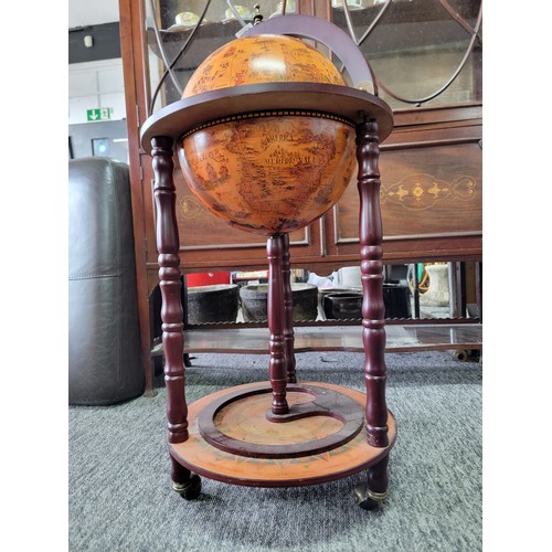 425 - Modern reproduction drinks globe standing on three castors, with a terrestrial globe scene to the to... 