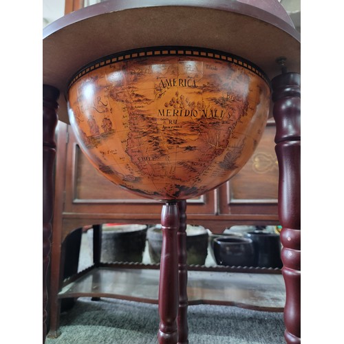 425 - Modern reproduction drinks globe standing on three castors, with a terrestrial globe scene to the to... 