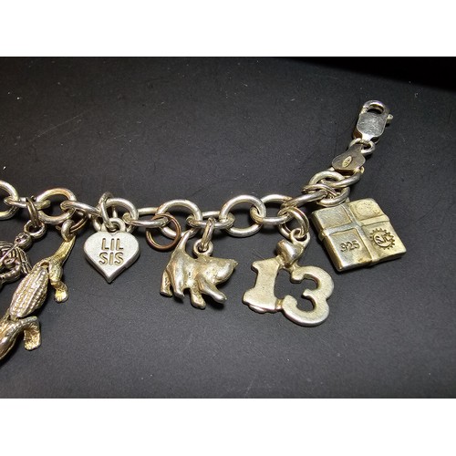 311 - A good quality vintage 925 silver charm bracelet featuring 14 different charms to include an articul... 