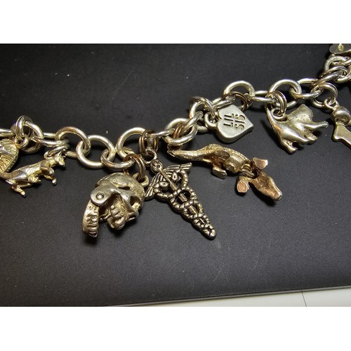 311 - A good quality vintage 925 silver charm bracelet featuring 14 different charms to include an articul... 