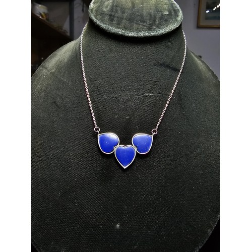 255 - A 925 silver triple heart necklace, each heart is inset with a lapislazuli stone presenting a vibran... 