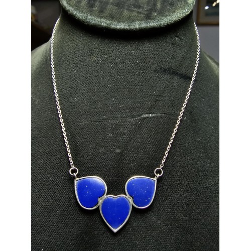 255 - A 925 silver triple heart necklace, each heart is inset with a lapislazuli stone presenting a vibran... 