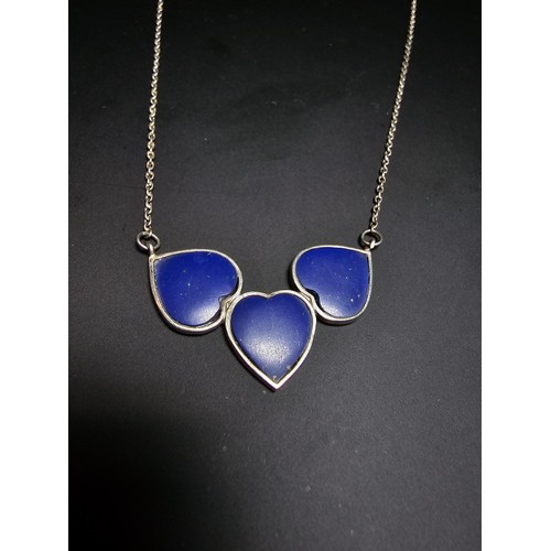 255 - A 925 silver triple heart necklace, each heart is inset with a lapislazuli stone presenting a vibran... 